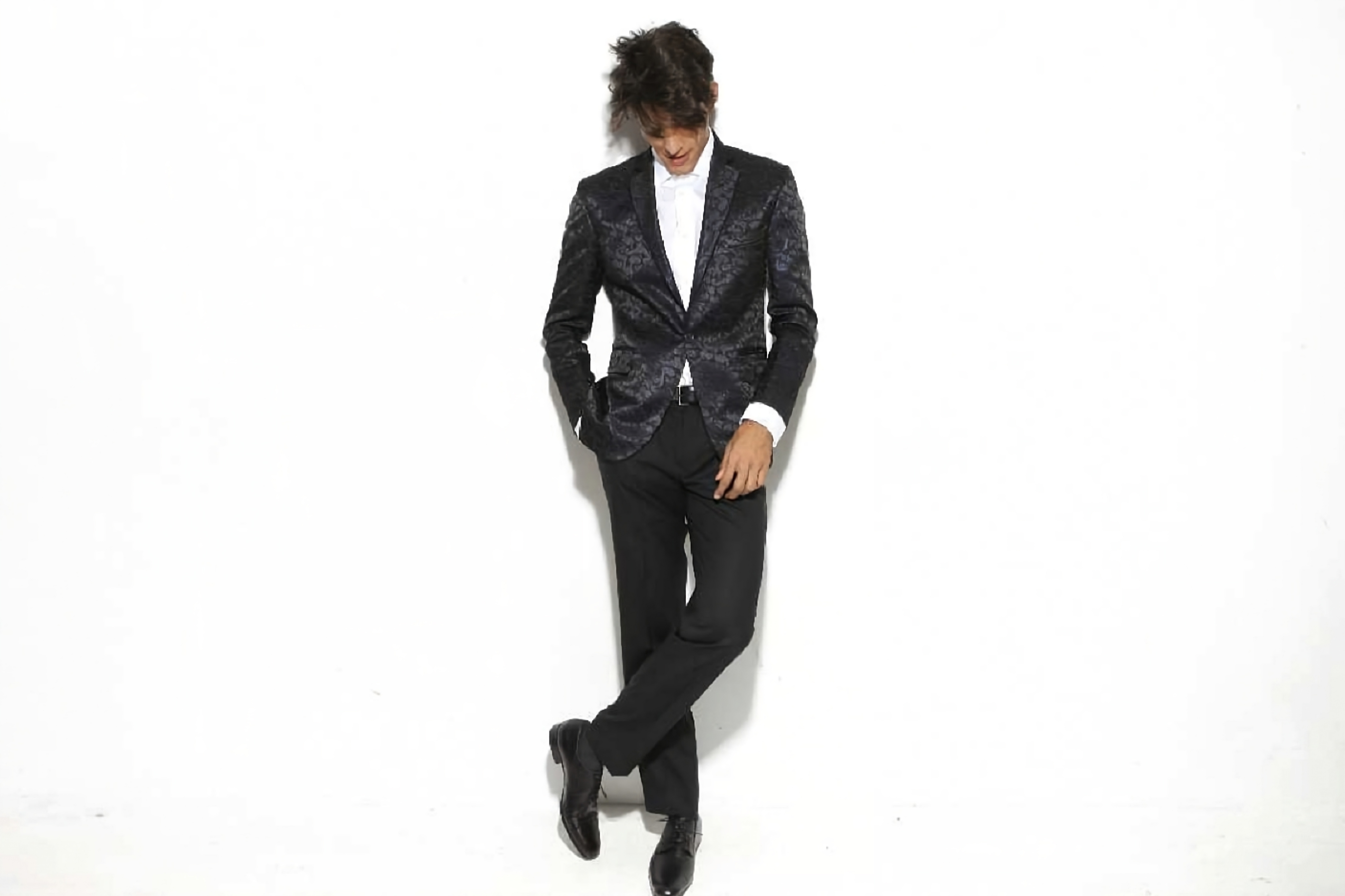 Well-dressed man wearing a tailored suit standing confidently in a modern, stylish interior with soft lighting and a calm, professional atmosphere